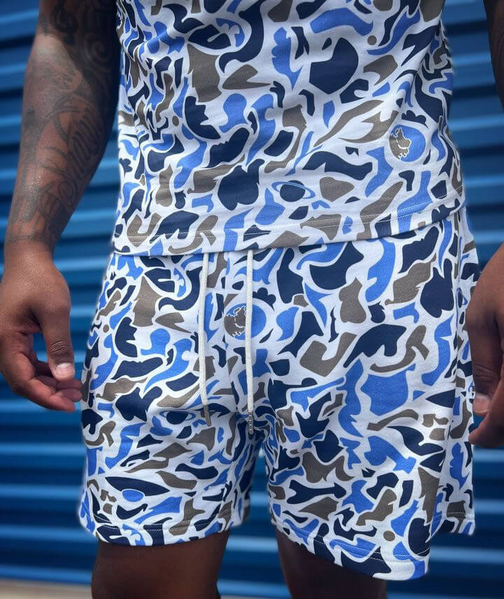 Model wearing Relaxed fit camouflage shorts and Top. Shorts made from 100% cotton, featuring an adjustable elastic waist, deep side pockets, and metal-tipped drawstrings.