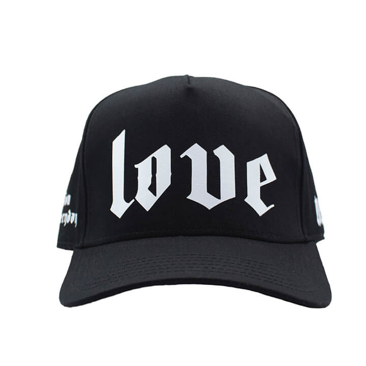 Front of Classic black premium trucker hat with bold white printed 'LOVE' logo on the front panel and mesh back.