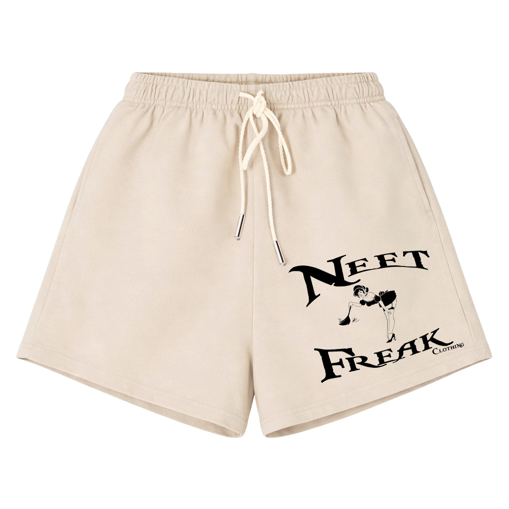 Beige drawstring shorts with a black graphic print on the left leg that reads 'NEET FREAK' with a small illustration, shown on a plain white background.